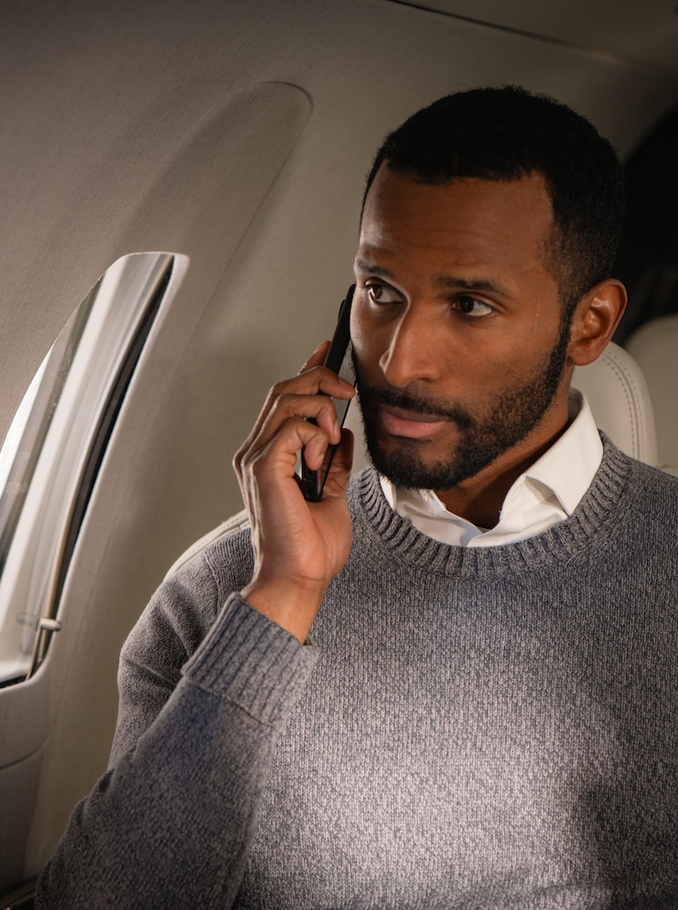 Business man on cell phone in private plane looking out window