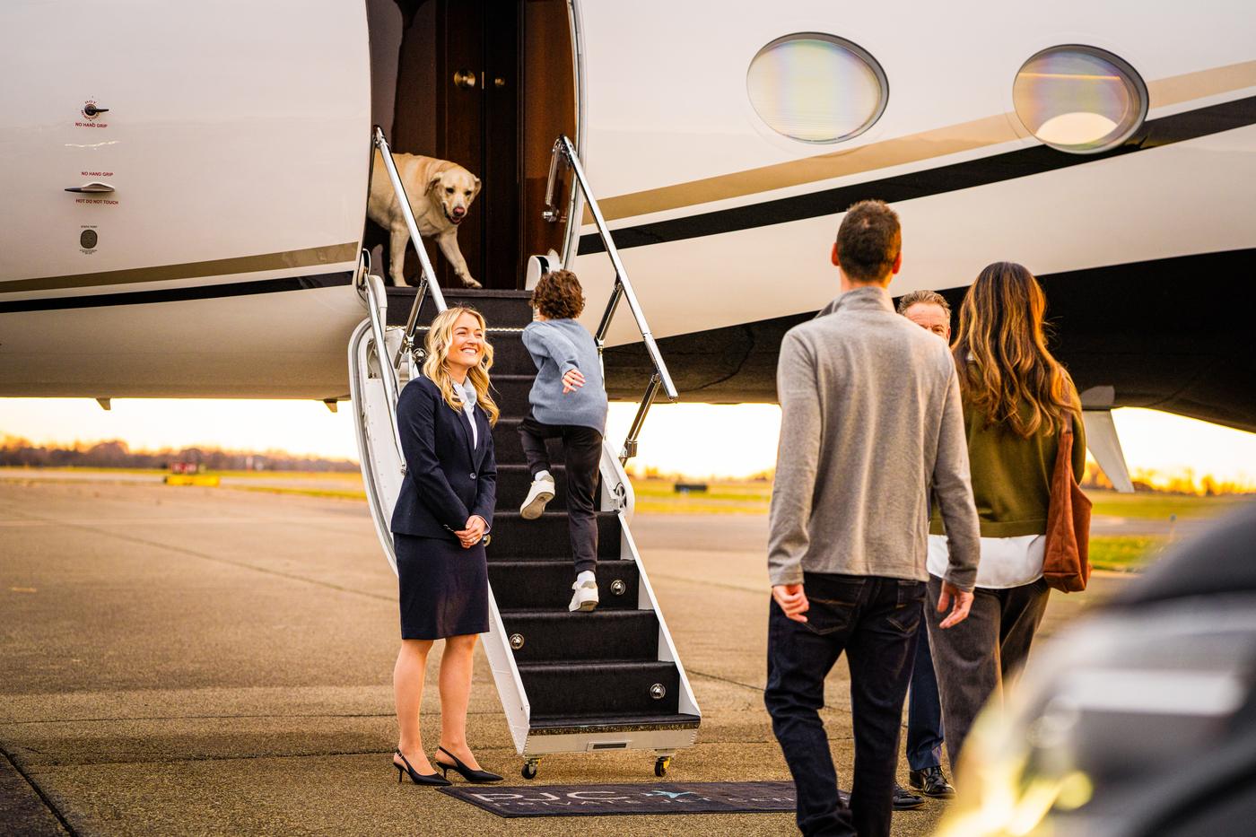A family boarding a Private Jet Center aircraft, greeted by crew